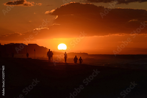 Silhouettes of people at sunset on the Atlantic ocean