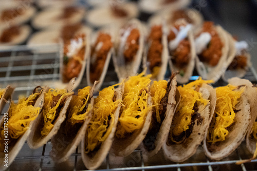 Assortment of traditional Thai street snacks, Khanom Bueang, featuring crispy taco-like shells filled with coconut cream and topped with sweet and salty ingredients.