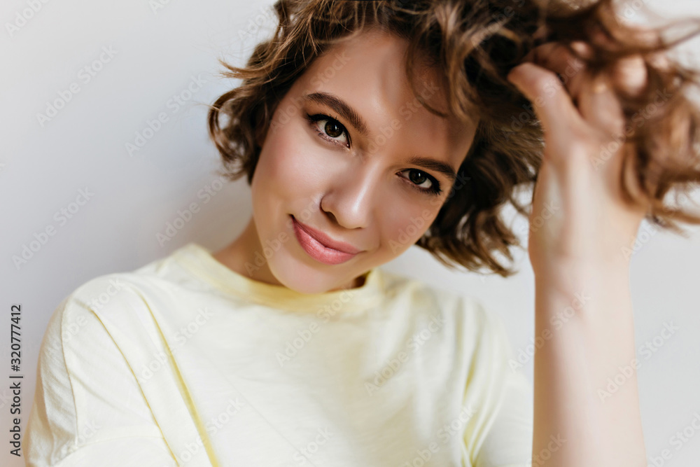 Studio shot of charming caucasian girl isolated on white background. Indoor portrait of pretty lady playing with short dark hair with gently smile. Studio shot of charming caucasian girl isolated on white background. Indoor portrait of pretty lady playing with short dark hair with gently smile.