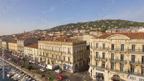 Sunrise drone shot on Sète. Nice traveling with cars driving along the channel with little fishing barques.Nice city colors in backround with the « Grand Hotel » and the Mont Saint Clair. The Venice o