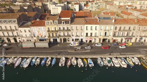 Sunrise drone shot on Sète. Nice traveling with cars driving along the channel with little fishing barque.Nice city colors in backround. The Venice of Languedoc.