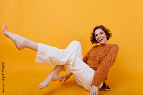 Billede på lærred Smiling barefooted girl with eacstatic face expression posing with legs up