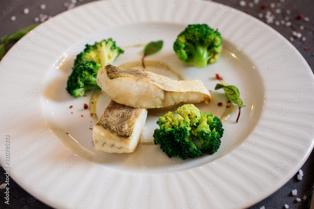 Healthy food, white fish with broccoli on the white plate.