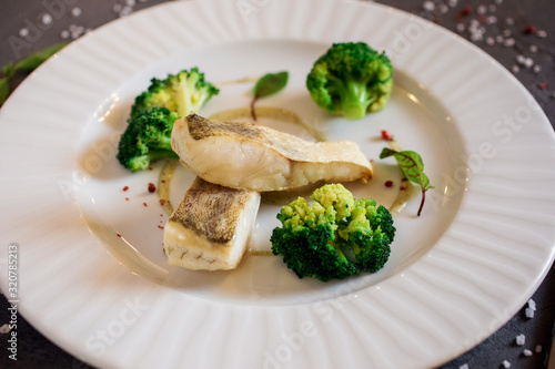 Healthy food, white fish with broccoli on the white plate.
