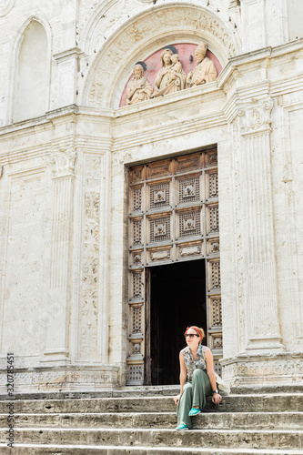 Young female traveler sitting on church steps in old town in Tuscany, Italy