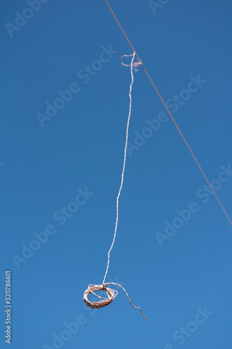 String is hanging on the cable. Minimalist image with clear blue sky as large copy space area. Very shallow depth of field.