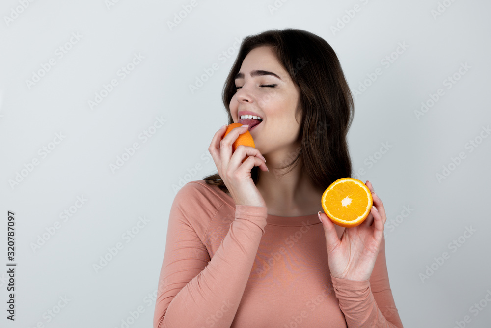 young woman holding licking with tongue one half of orange standing on isolated white background young woman holding licking with tongue one half of orange standing on isolated white background