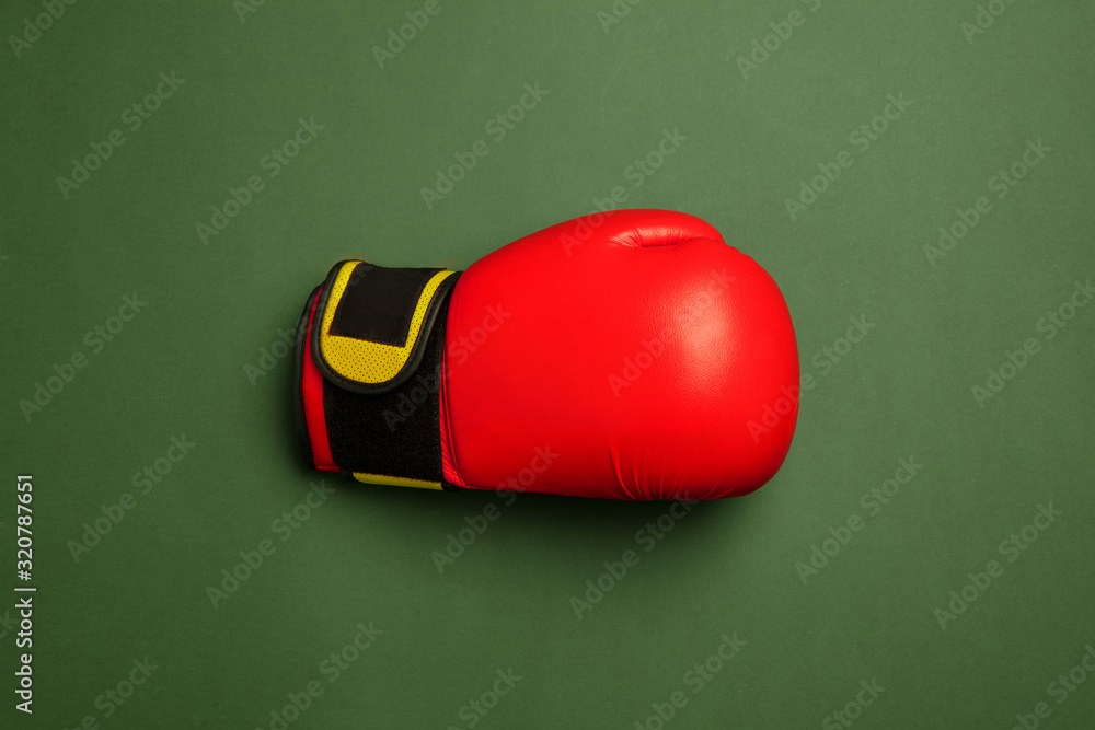 Bright red and yellow boxing glove. Professional sport equipment isolated on green studio background. Concept of sport, activity, movement, healthy lifestyle, wellbeing. Modern colors.