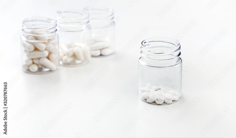 Four packages with various white pills and capcules on a white background. Health concept. Copy space. Four packages with various white pills and capcules on a white background. Health concept. Copy space.