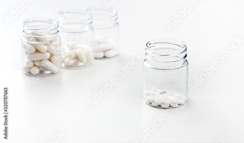 Four packages with various white pills and capcules on a white background. Health concept. Copy space.
