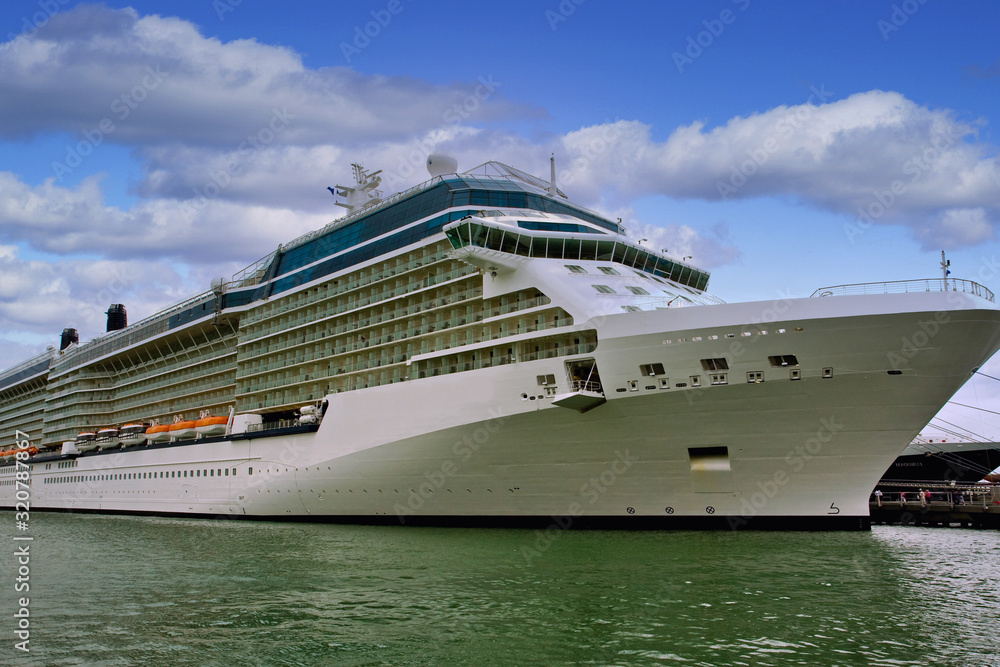 A large cruise ship tied up at a dock on a cloudy day