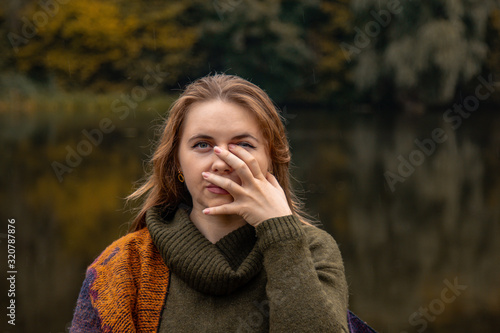 hide and seek. the girl covered her face with her hands. Close-up portrait on a lake background. The concept of female pain, sadness, violence, depression, loneliness.
