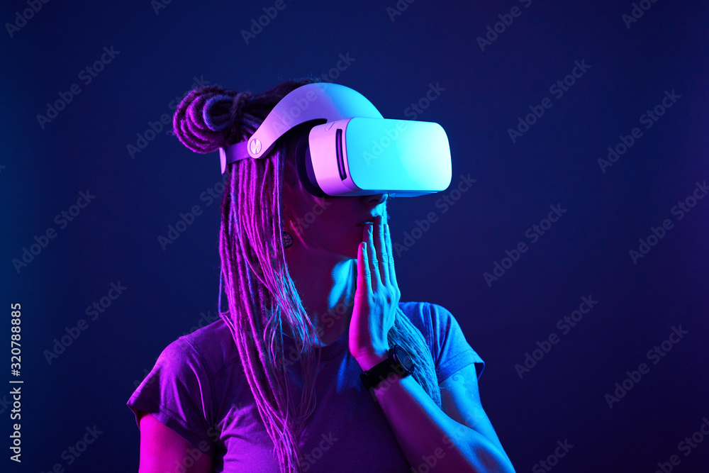 Woman is using virtual reality headset. Neon light studio portrait. Woman is using virtual reality headset. Neon light studio portrait.