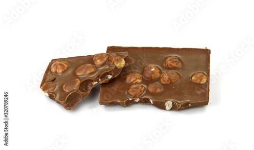 A broken piece of chocolate with hazelnuts isolated on white background. Milk chocolate tiles with nuts isolated on white.
