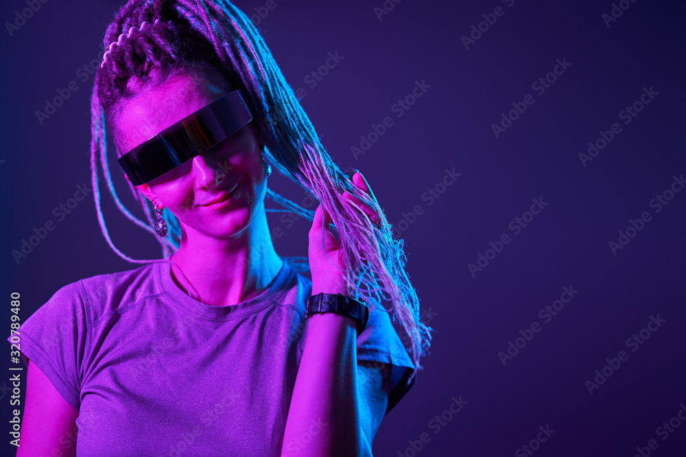 Happy girl with pigtails in sunglasses looking at camera in neon light Happy girl with pigtails in sunglasses looking at camera in neon light