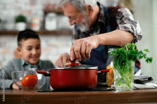 Grandpa and grandson in kitchen. Grandfather and his grandchild having fun while cooking.