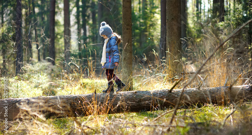 Cute little girl having fun during forest hike on beautiful spring day. Child exploring nature.