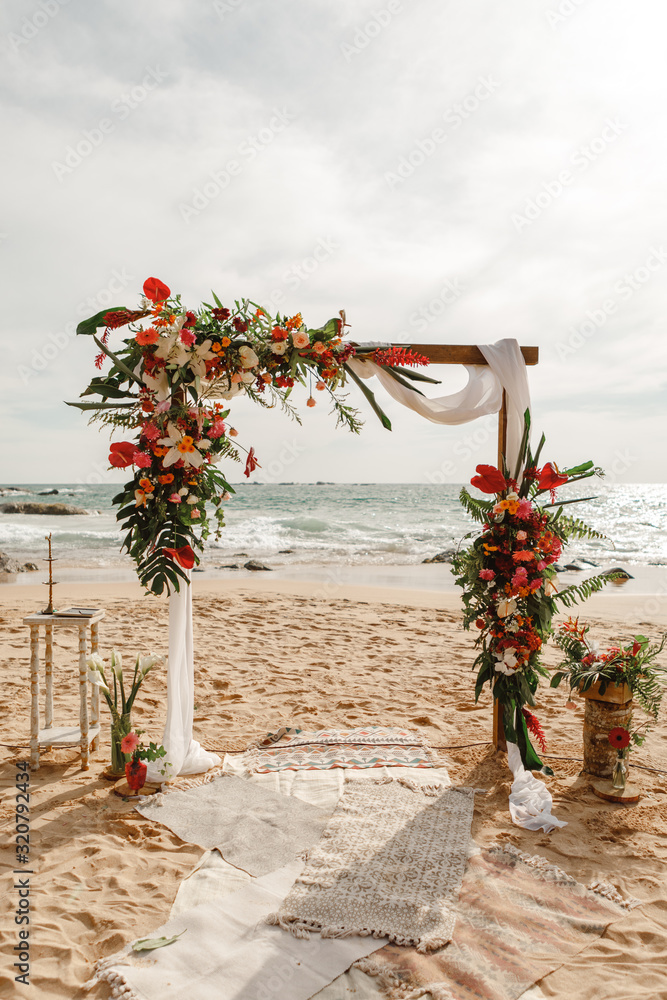 Wedding arch decorated with flowers for beach ceremony against the sea landscape. Tropical wedding ceremony in boho rustic style Stock Foto Adobe Stock