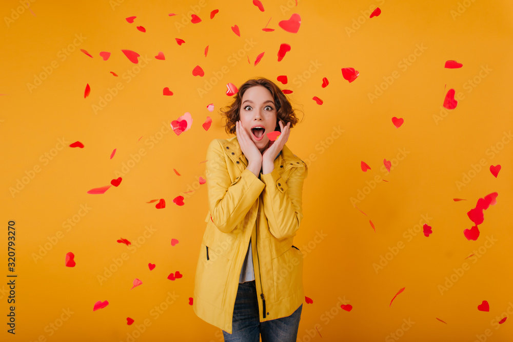 Surprised pretty girl in casual clothes having fun in valentine's day. Indoor photo of spectacular woman surrounded by red hearts. Surprised pretty girl in casual clothes having fun in valentine's day. Indoor photo of spectacular woman surrounded by red hearts.