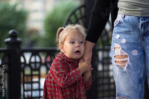 Funny and scared face of the caucasian child of two years old holding mother hand photo
