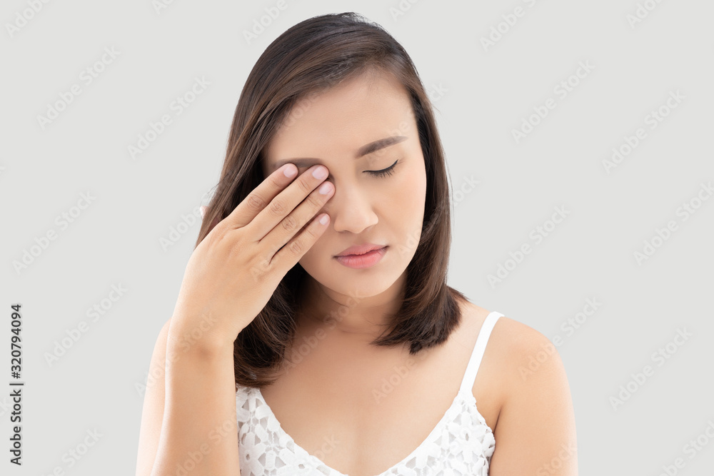 Asian woman suffering from strong eye pain against a gray background. Female has a pain in the eye. Healthcare concept. Having migraine Asian woman suffering from strong eye pain against a gray background. Female has a pain in the eye. Healthcare concept. Having migraine