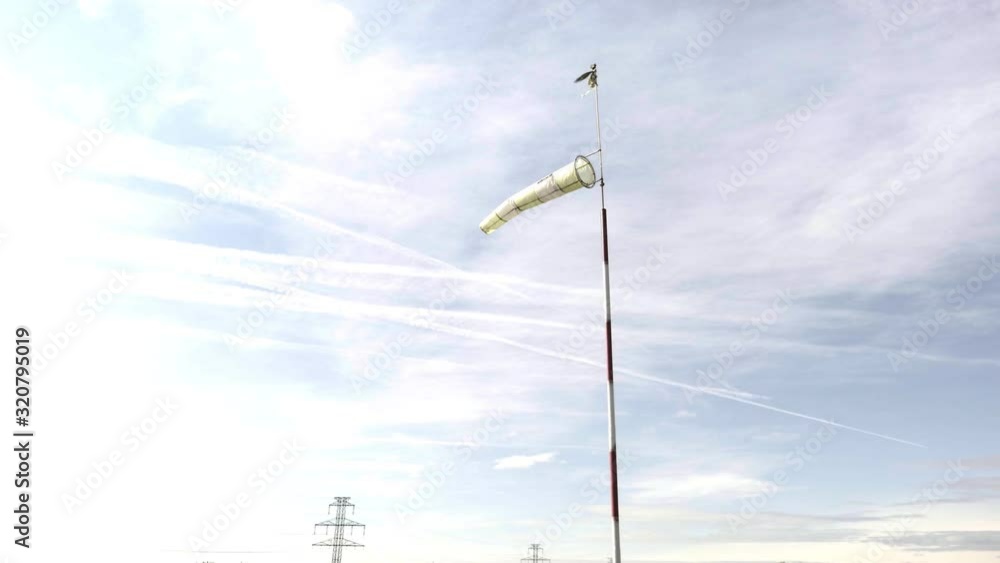 Windsock on sunset sky background. Gauge weather instrument blazing in wind. Meteorology wind sock, wind speed Windsock on sunset sky background. Gauge weather instrument blazing in wind. Meteorology wind sock, wind speed