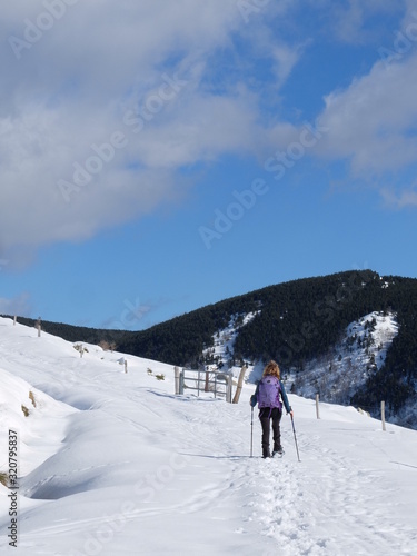 Jeune femme randonneuse en raquette dans la neige en montagne sous le soleil des Pyrénées Orientales de Cerdagne © Ourson+