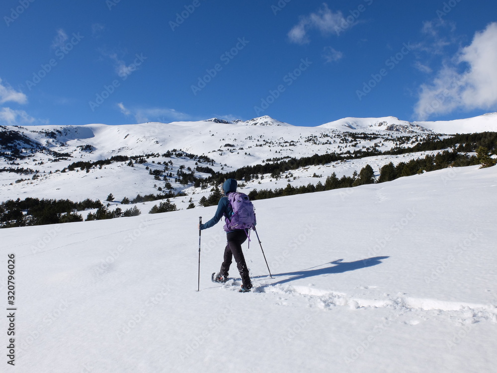 Jeune femme randonneuse en raquette dans la neige en montagne sous le soleil des Pyrénées Orientales de Cerdagne