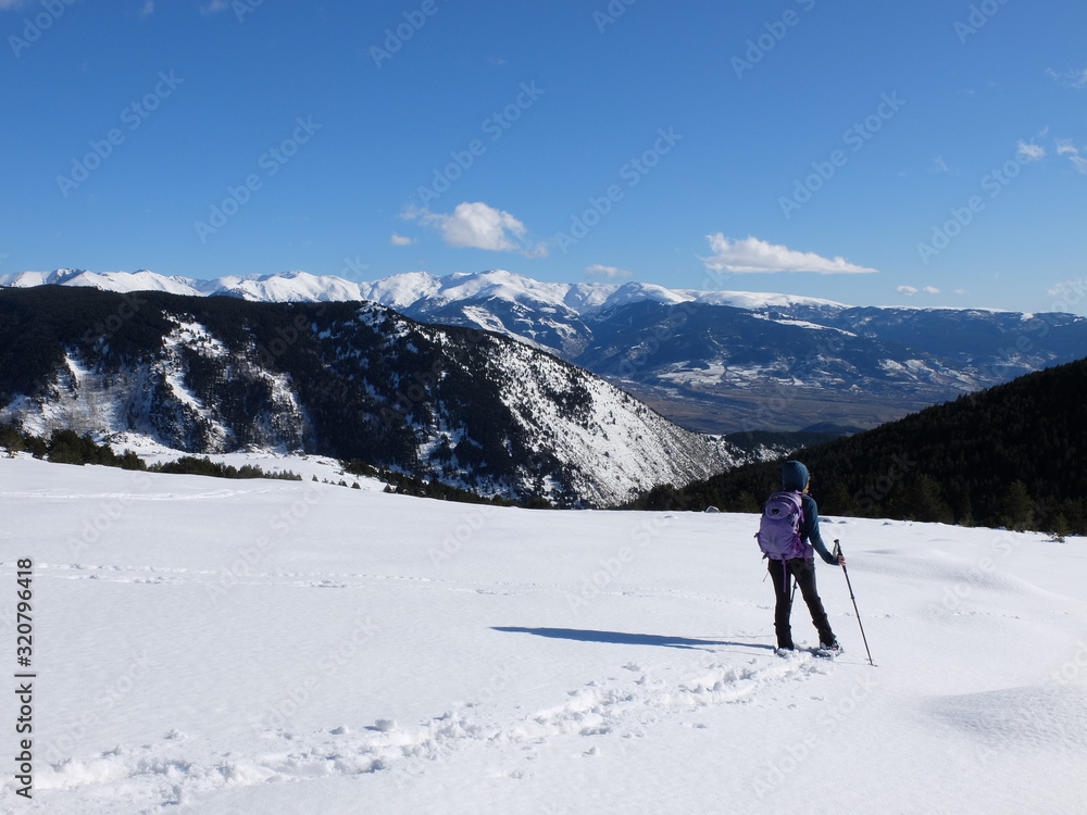 Jeune femme randonneuse en raquette dans la neige en montagne sous le soleil des Pyrénées Orientales de Cerdagne