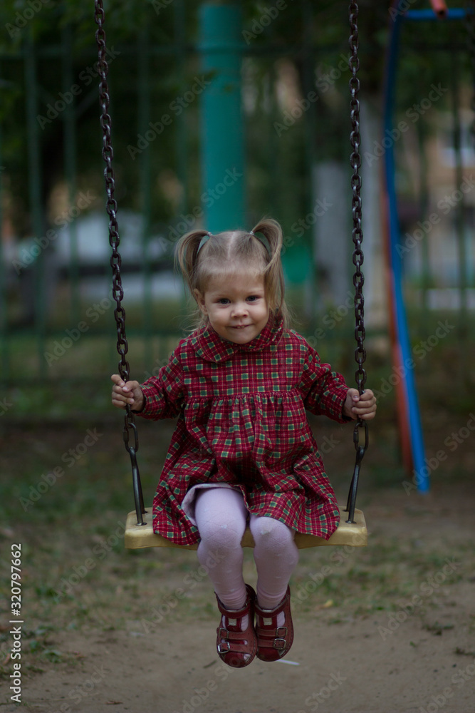 Happy caucasian child of two years old sitting on chain swing and swinging Happy caucasian child of two years old sitting on chain swing and swinging