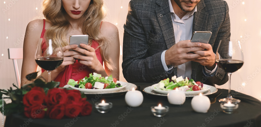 Man And Woman Stuck In Their Smartphones On Date In Restaurant Man And Woman Stuck In Their Smartphones On Date In Restaurant
