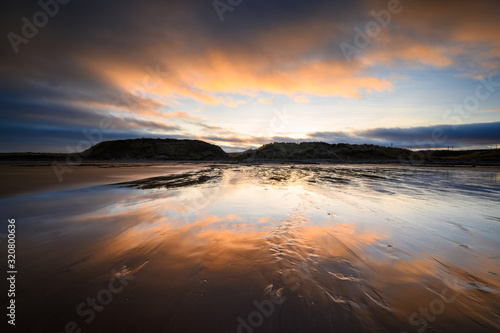 Reflected Sunset on wet sand at Cocklawburn Beach, a rural beach within Northumberland Coast Area of Outstanding Natural Beauty (AONB), located just south of Berwick-upon-Tweed