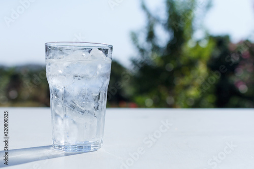 a glass of water with ice on the table.