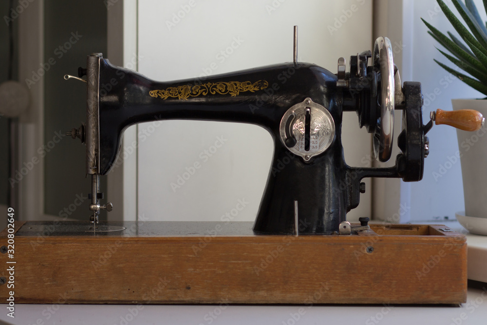 Old manual sewing machine with machine pulley and the wooden handle