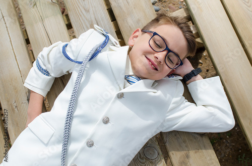фотографія Happy child resting on a wooden plank dressed in communion suit