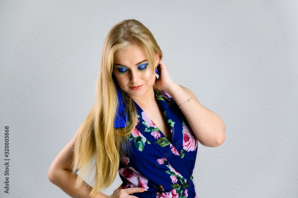 Nice girl with fluttering hair and great make-up in front of the camera on a white background in a multi-colored dress. Model stands in different poses. Nice girl with fluttering hair and great make-up in front of the camera on a white background in a multi-colored dress. Model stands in different poses.
