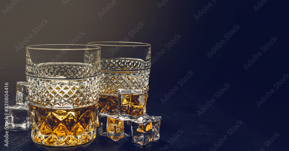 two expensive glasses of whiskey with ice on a black stone tray