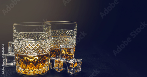 two expensive glasses of whiskey with ice on a black stone tray © Mikhaylovskiy 