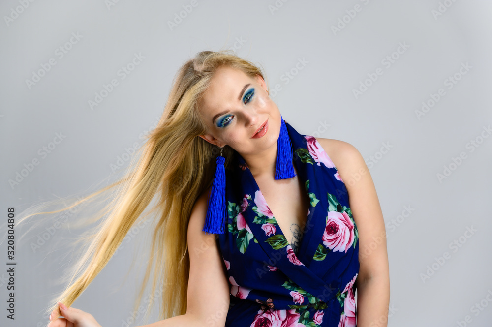 The model stands in different poses. Nice girl with fluttering hair and great make-up in front of the camera on a white background in a multi-colored dress. The model stands in different poses. Nice girl with fluttering hair and great make-up in front of the camera on a white background in a multi-colored dress.