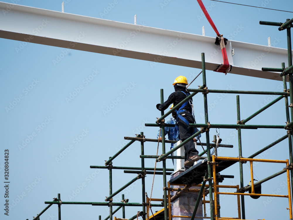 Construction workers working on scaffolding with blue sky at construction site