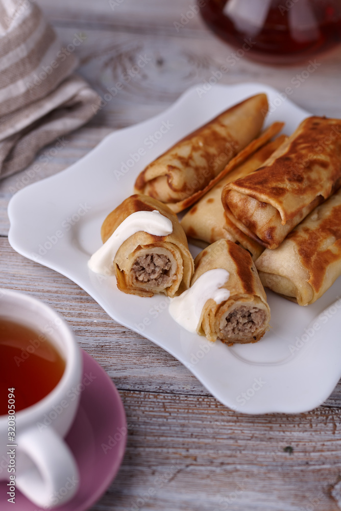 Russian pancakes with filling, lying on a plate with a slide Russian pancakes with filling, lying on a plate with a slide