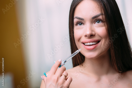 woman beautiful mouth and lips gets an injection. Increase the lips by hyaluronic acid
