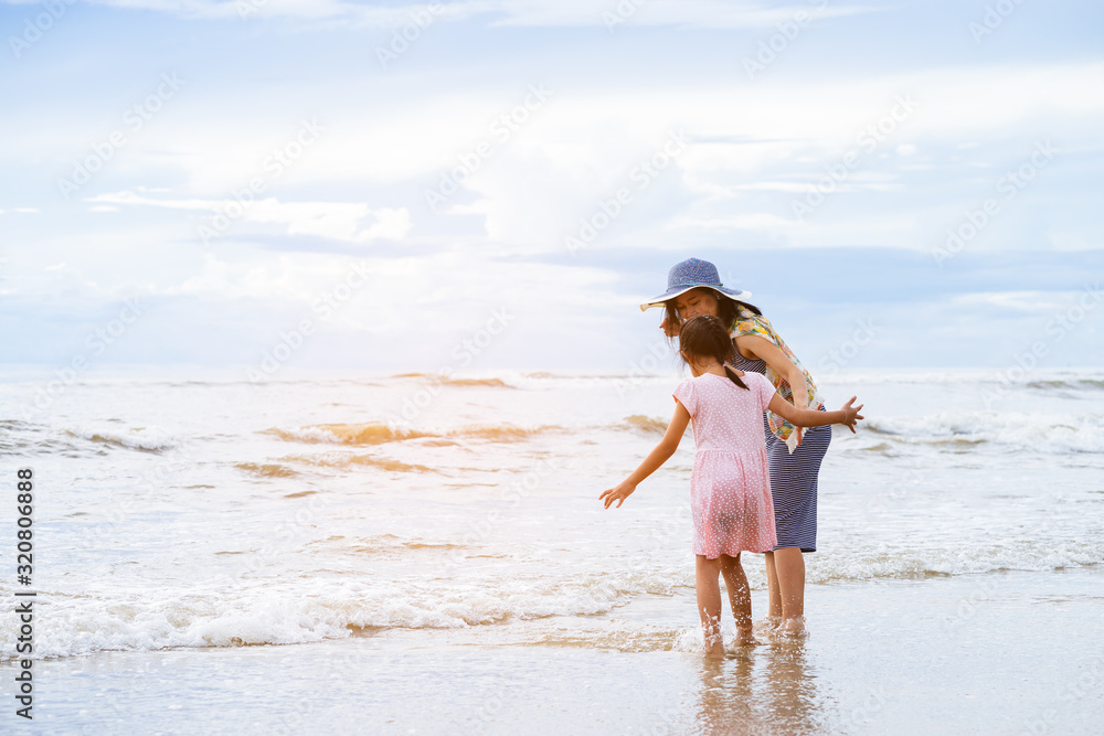 Asian Mother smiling with her daughter and hold one's hands on the beach Asian Mother smiling with her daughter and hold one's hands on the beach