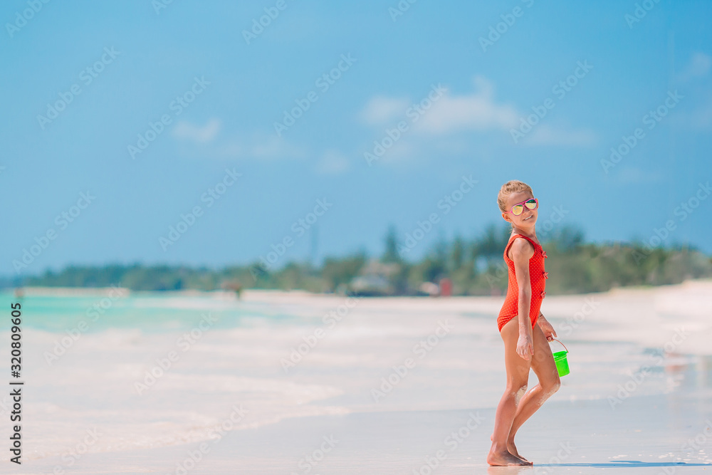 Adorable little girl playing with beach toys on white tropial beach