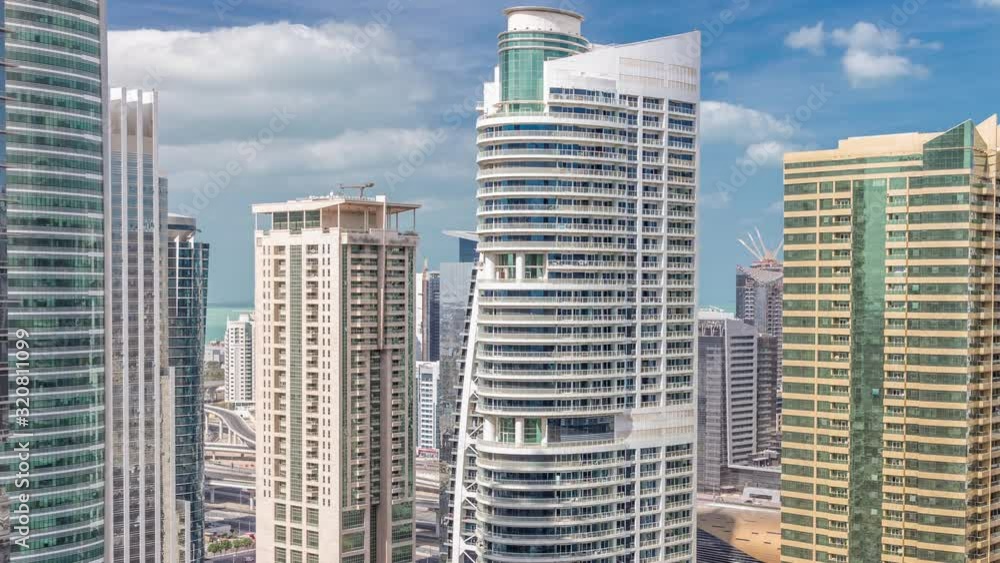 Residential apartments and offices in Jumeirah lake towers district timelapse in Dubai. Aerial view from above with modern skyscrapers and clouds on blue sky Residential apartments and offices in Jumeirah lake towers district timelapse in Dubai. Aerial view from above with modern skyscrapers and clouds on blue sky
