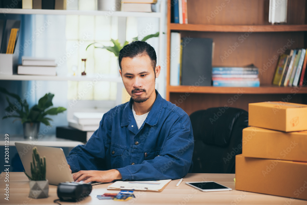 The man working laptop computer from home on wooden floor with postal parcel, Selling online ideas concept. The man working laptop computer from home on wooden floor with postal parcel, Selling online ideas concept.
