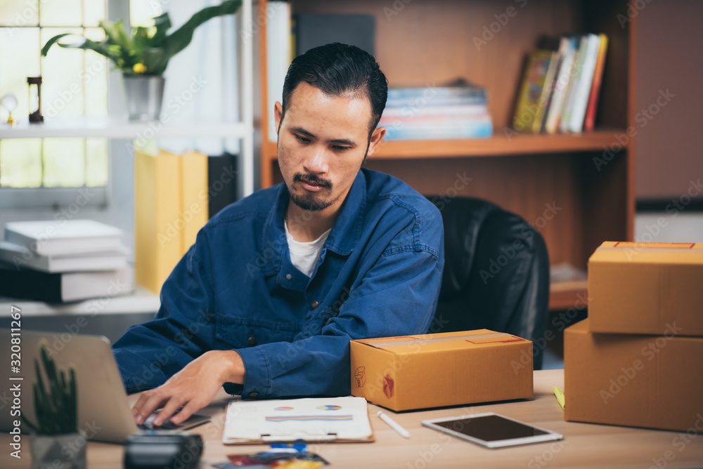 The man working laptop computer from home on wooden floor with postal parcel, Selling online ideas concept. The man working laptop computer from home on wooden floor with postal parcel, Selling online ideas concept.