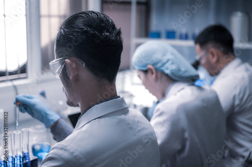 Team of Medical Research Scientists Collectively Working on a New Generation Experimental Drug Treatment. Laboratory Looks Busy, Bright and Modern.