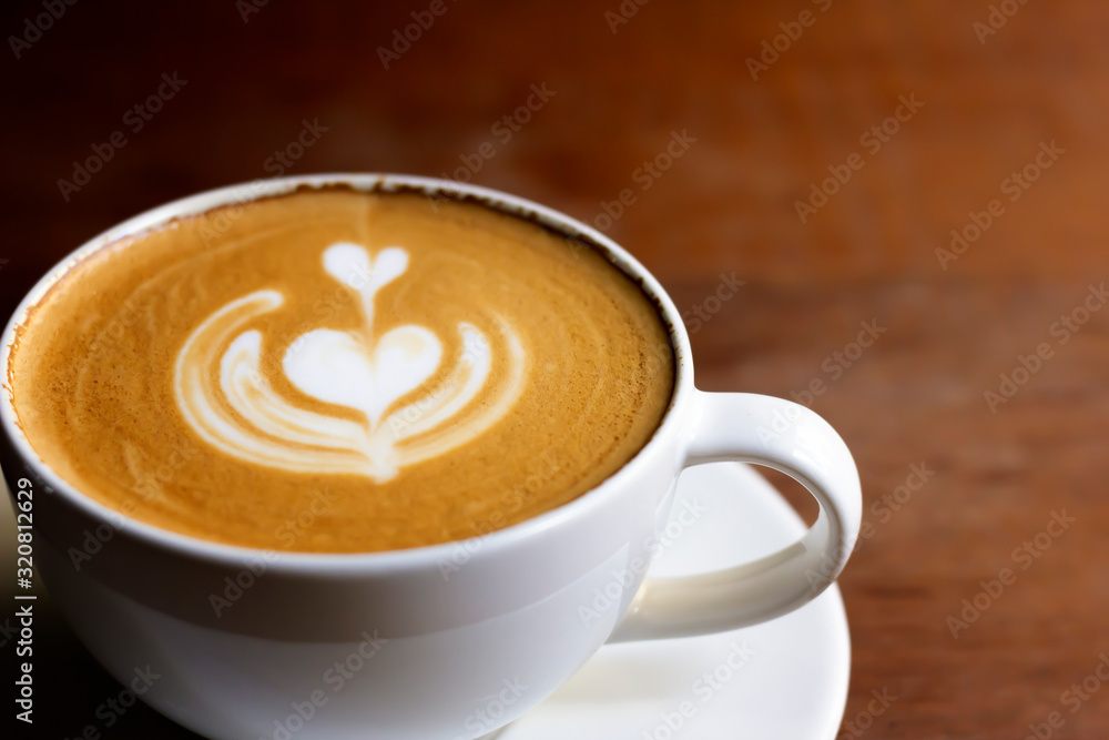 White cup of cappuccino with latte art on wooden background at coffee cafe. White cup of cappuccino with latte art on wooden background at coffee cafe.
