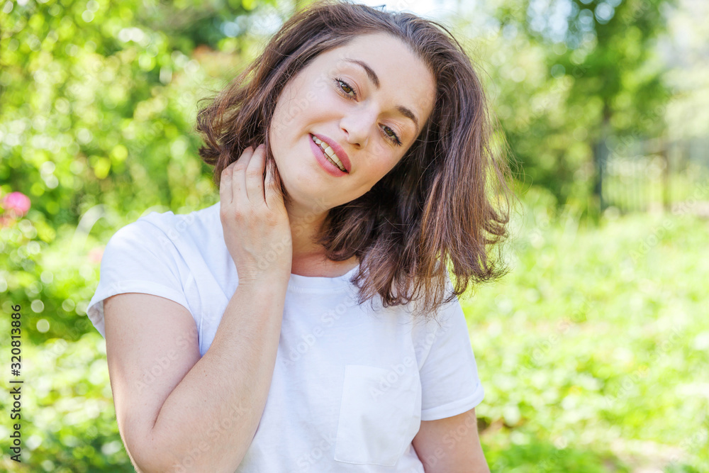 Happy girl smiling outdoor. Beautiful young brunete woman with brown hair resting on park or garden green background. European woman. Positive human emotion facial expression body language.